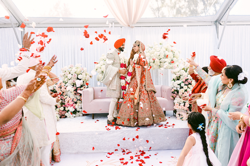 Couple exchanging garlands with guests during South Asian wedding traditions