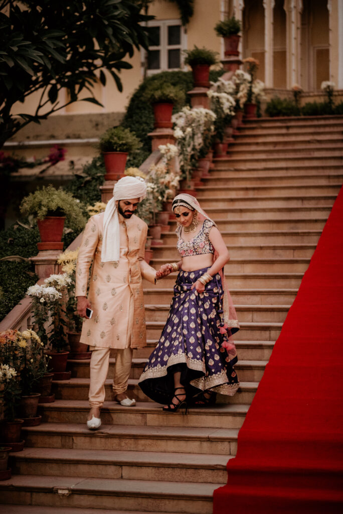 South Asian wedding couple walking down staircase in traditional attire during wedding celebration