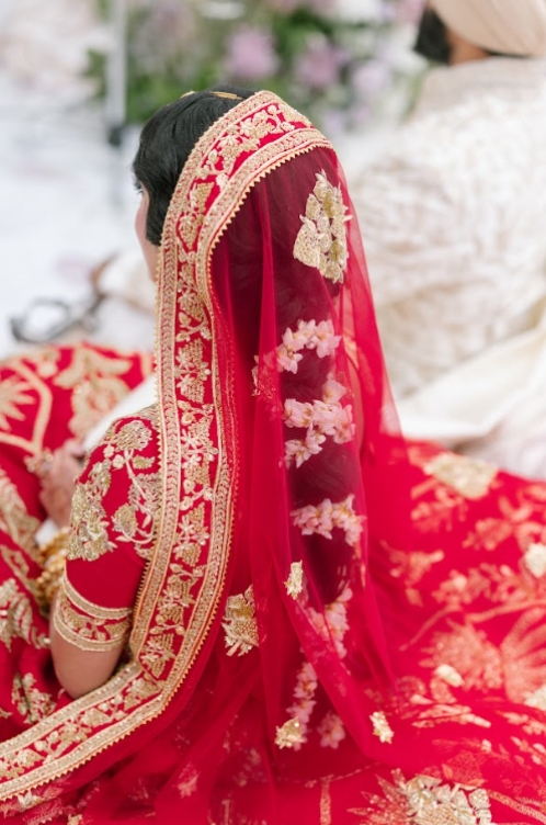Bride in red embroidered lehenga and veil during the Phere ceremony, reflecting sacred rituals in South Asian Wedding Traditions.