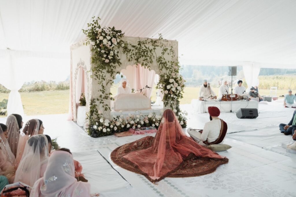 Sikh wedding ceremony under a floral canopy with guests seated, thoughtfully coordinated by a Sikh Wedding Planner.