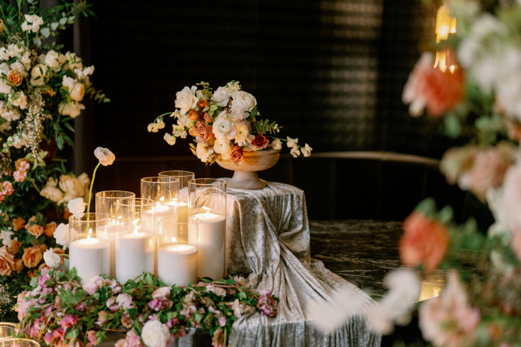 Romantic candlelight display with lush floral arrangements and layered textures in luxury South Asian wedding decor