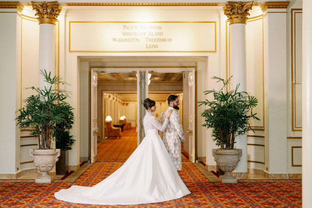Bride and groom at a grand venue entrance with classic architecture and elevated South Asian wedding decor styling