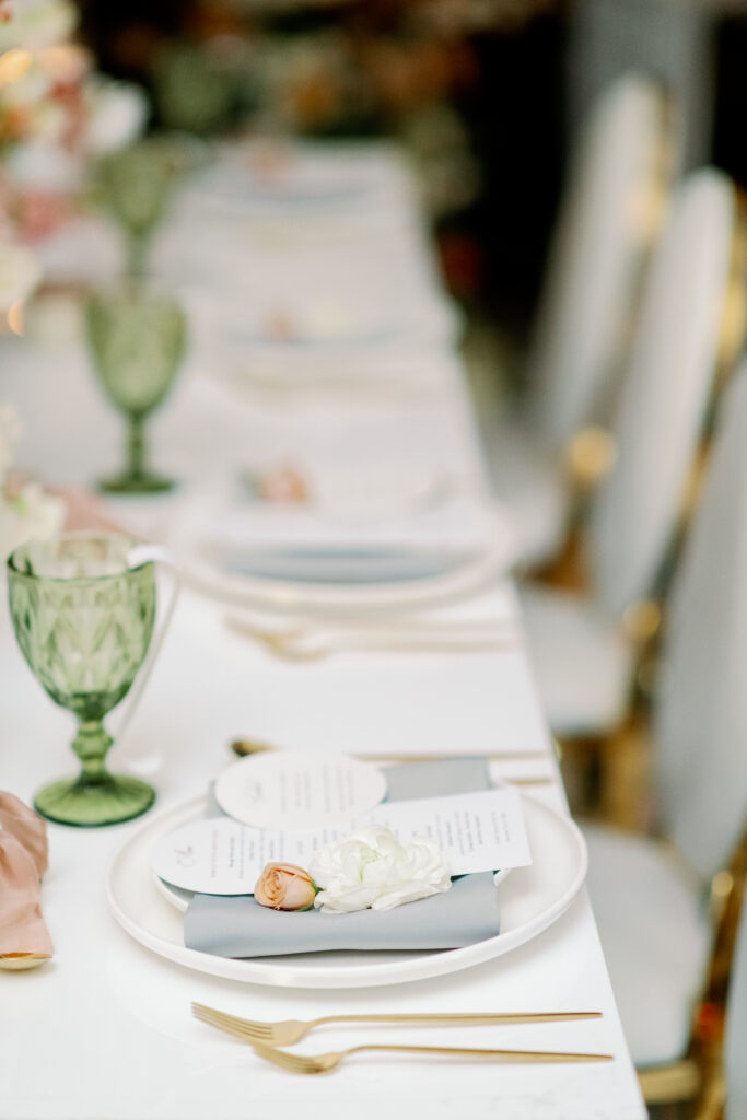 Minimalist place setting with soft florals, linen napkin, and glassware showcasing refined South Asian wedding decor details