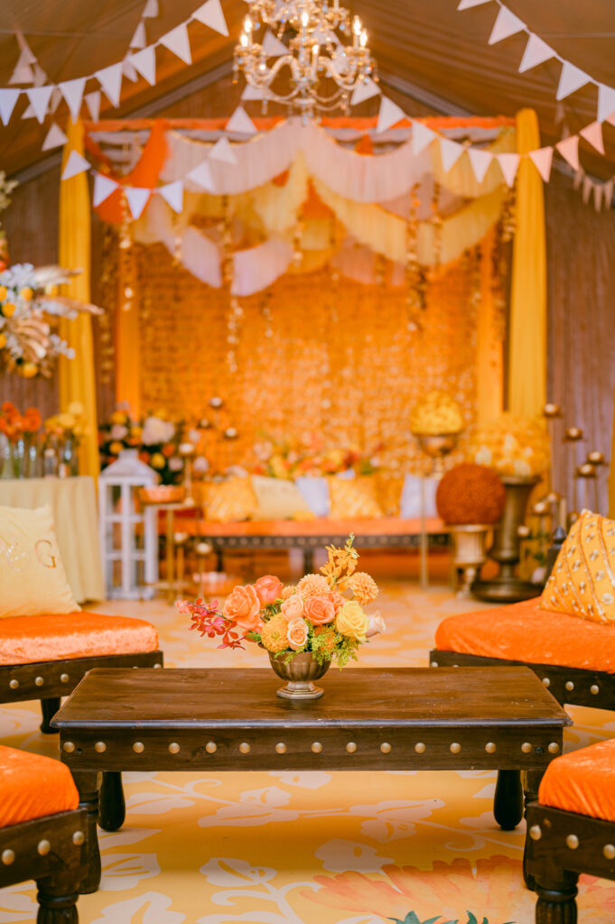 Vibrant mehndi lounge decor with yellow draping and florals for a Dubai destination wedding event